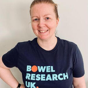 A smiling woman in a navy Bowel Research UK t-shirt